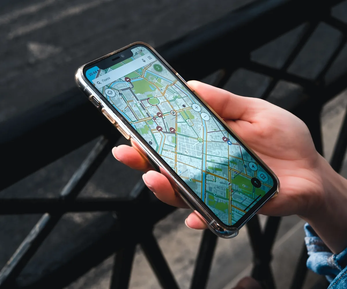 Hand hält ein Smartphone mit geöffneter Kartenansicht
