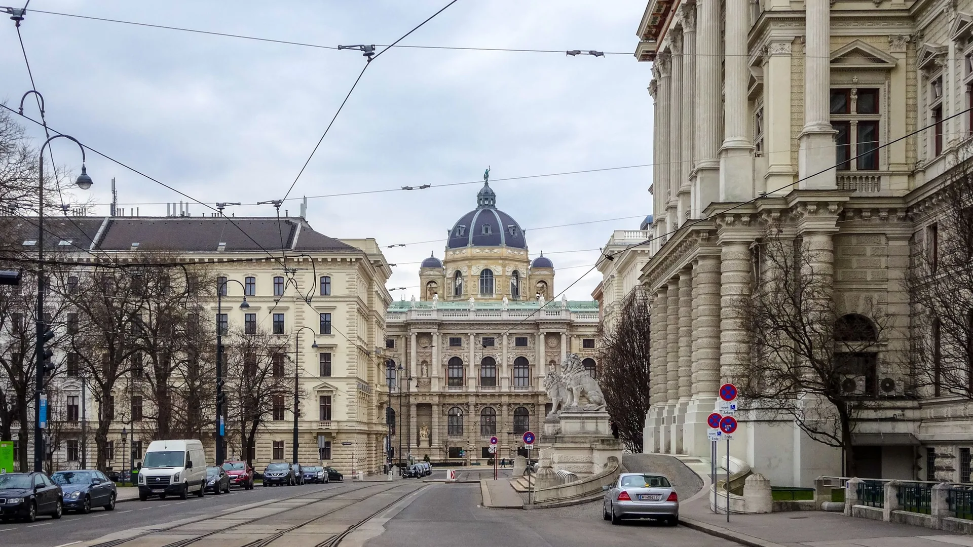 Straße in der Wiener Innenstadt mit Straßenbahngleisen, im Hintergrund die Kuppel des Naturhistorischen Museums